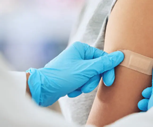 Arzt klebt Pflaster auf Arm von Patientin