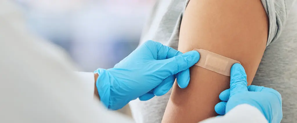 Arzt klebt Pflaster auf Arm von Patientin