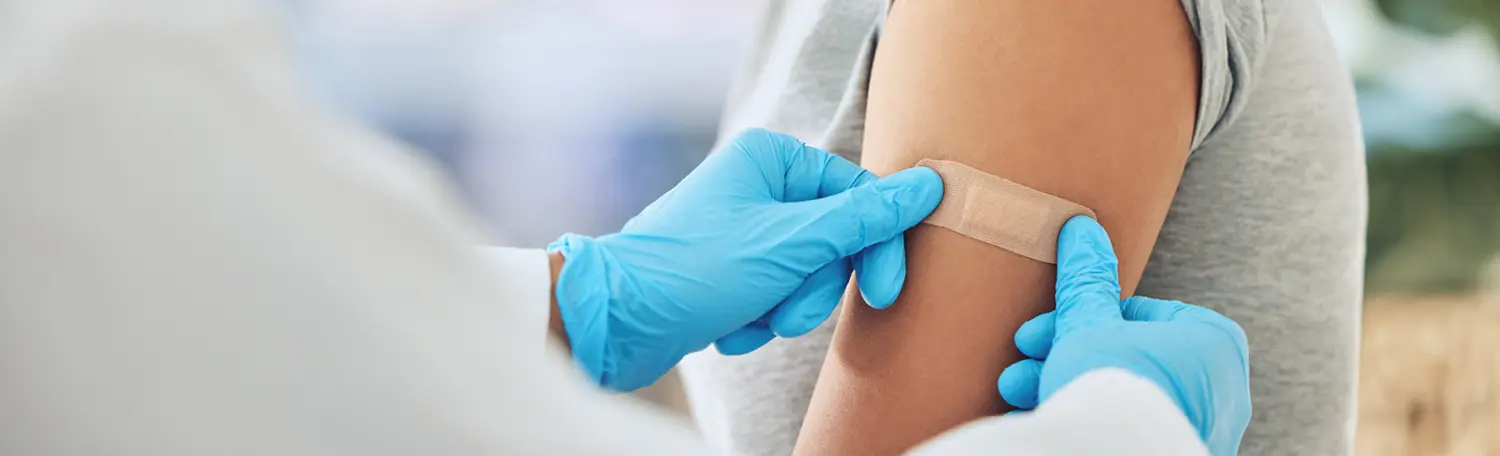 Arzt klebt Pflaster auf Arm von Patientin