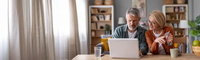 Paar am Laptop mit Versicherungskarte