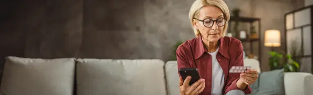 Frau auf Couch mit Tabletten und Handy