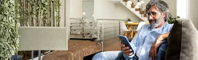 Mann mit Handy auf Sofa