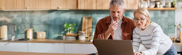 Paar in Küche am Laptop