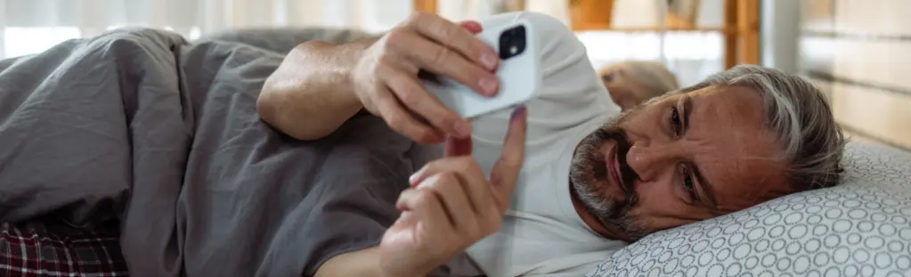 Mann im Bett mit Handy