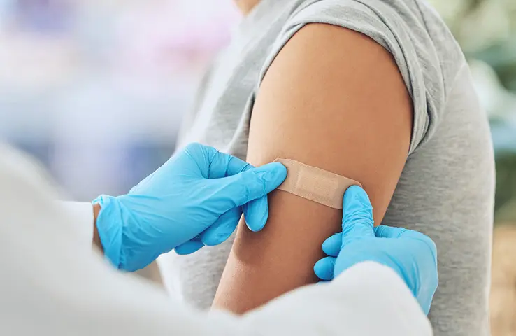 Arzt klebt Pflaster auf Arm von Patientin