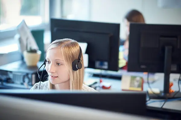 Kundendienstberaterin mit Headset sitzt am PC