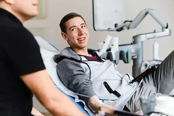 Pfleger versorgt Mann auf Liege mit Infusion