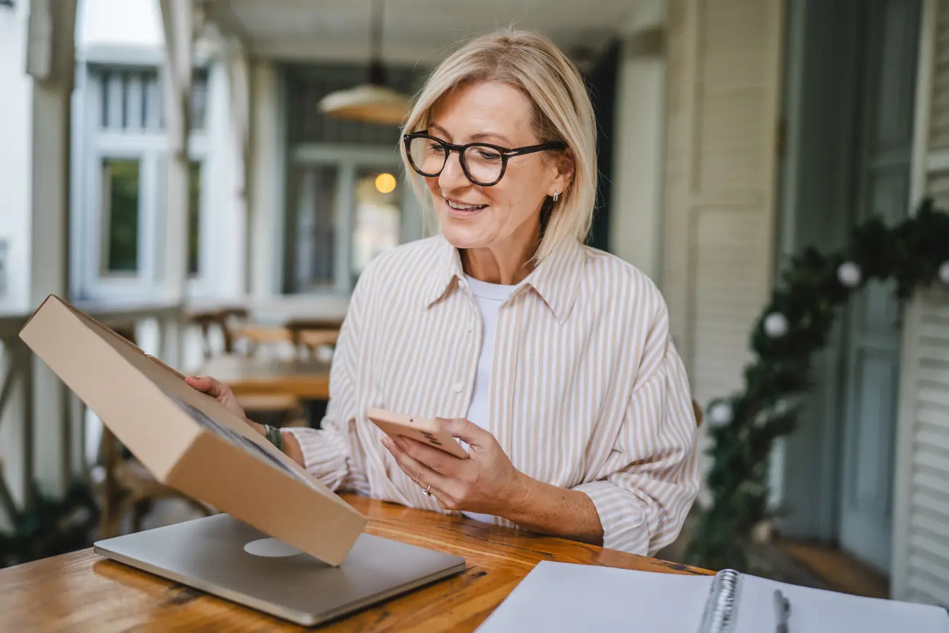 Frau am Tisch mit Paket und Smartphone