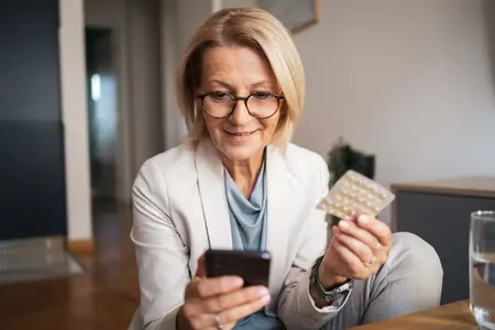 Frau mit Tabletten und Handy