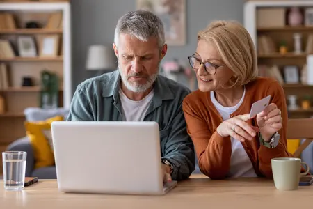 Paar am Laptop mit Versicherungskarte