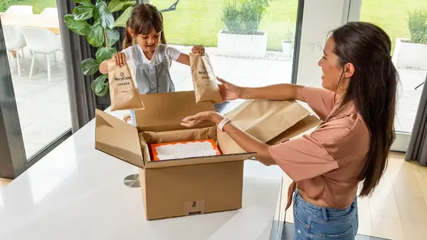 Mutter und Tochter packen Paket mit spezieller Verpackung aus