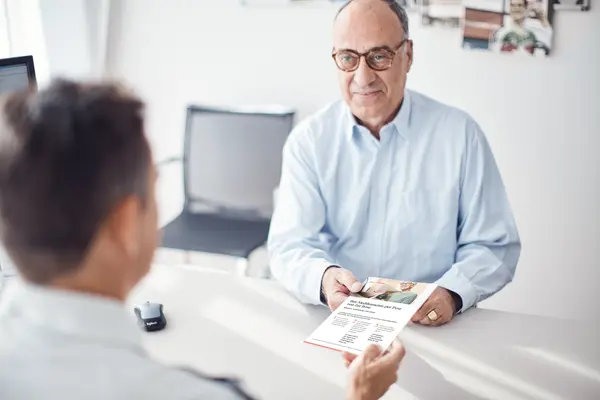 Arzt übergibt Broschüre an Patient